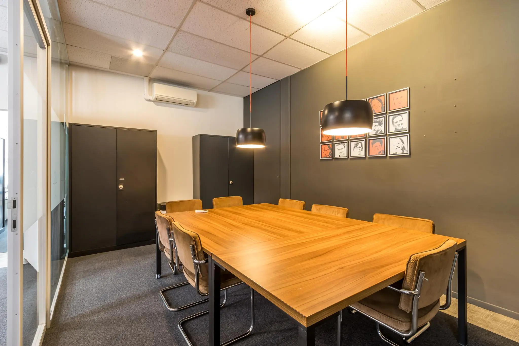 Vergaderruimte aan de Jan van Eycklaan met een houten tafel, leren stoelen en twee hanglampen.